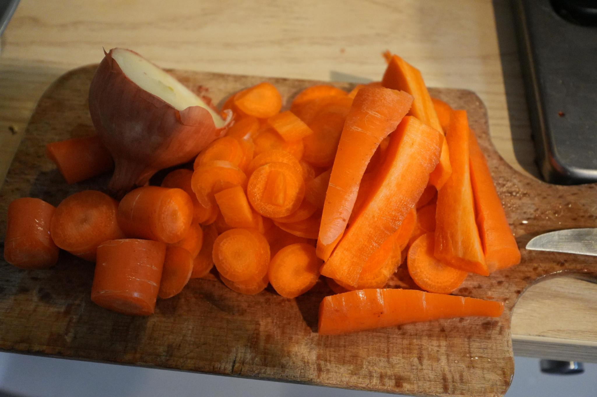chopped carrots next to an onion cut in half